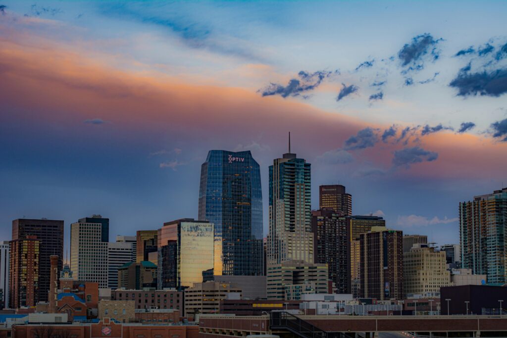 Stunning view of Denver's cityscape with skyscrapers under a colorful sunset sky.
