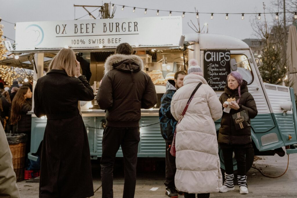 People enjoying food at a burger truck in Zürich's Christmas market, capturing the festive winter vibe.