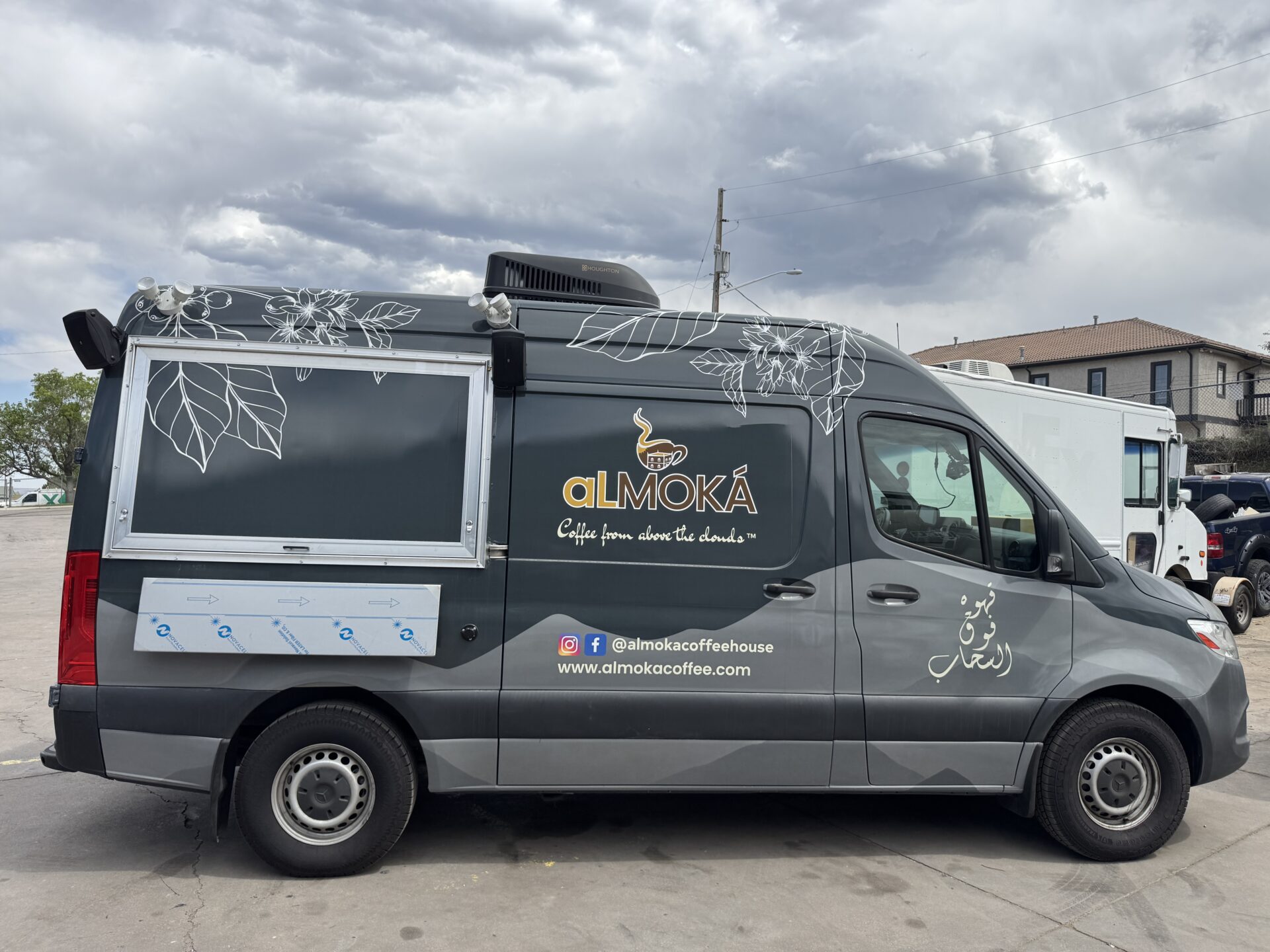alMOKA Sprinter coffee van driver side full view in sunlight showing dark grey wrap with white botanical art