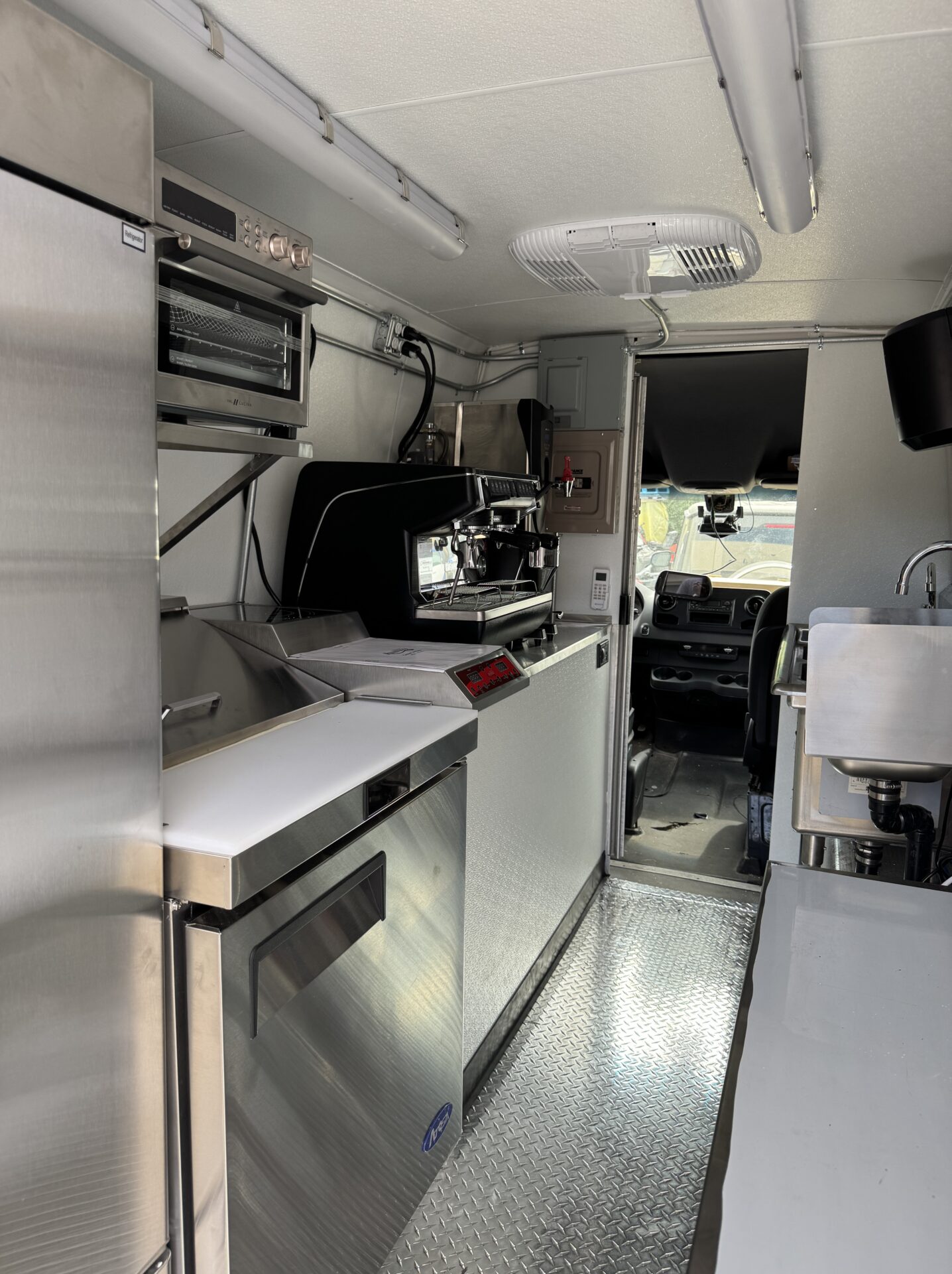 Interior of the alMOKA coffee van showing the espresso bar with espresso machine, sinks, and toaster oven