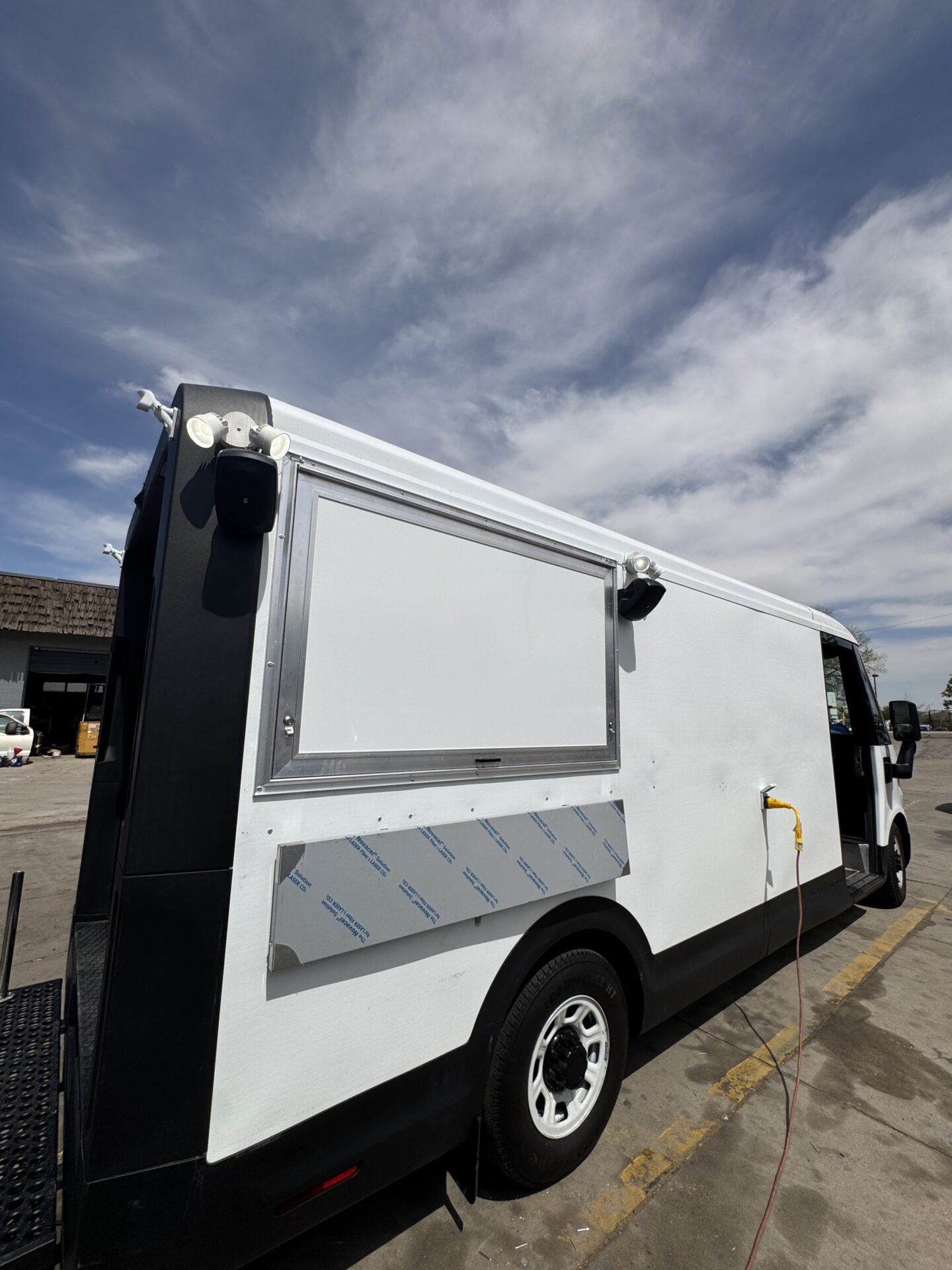 Closed 5 foot service window on the BrightDrop Crumbl Cookie food truck with flood lights and security cameras mounted above