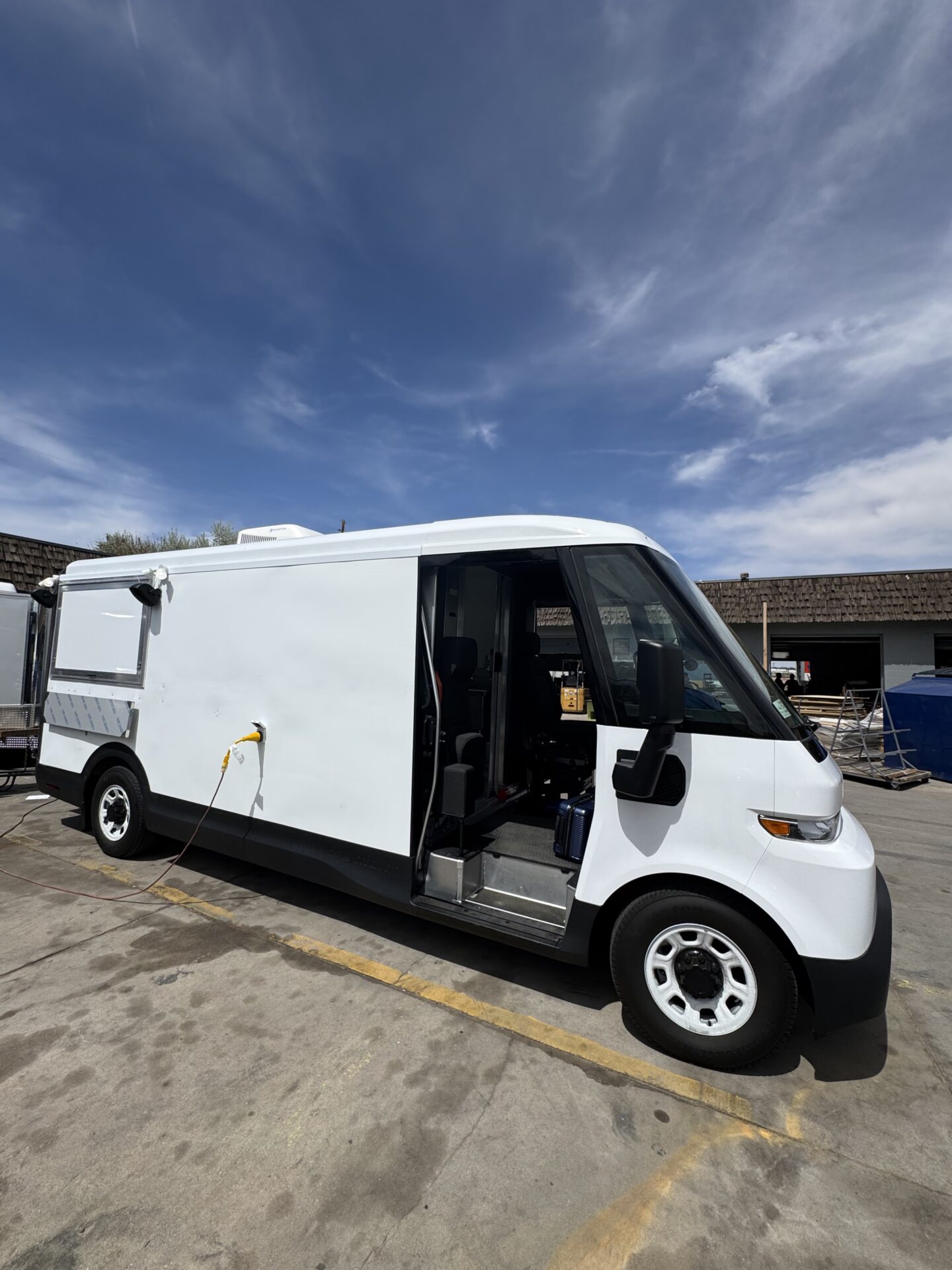 Side profile of the BrightDrop Zevo Crumbl Cookie food truck plugged into shore power
