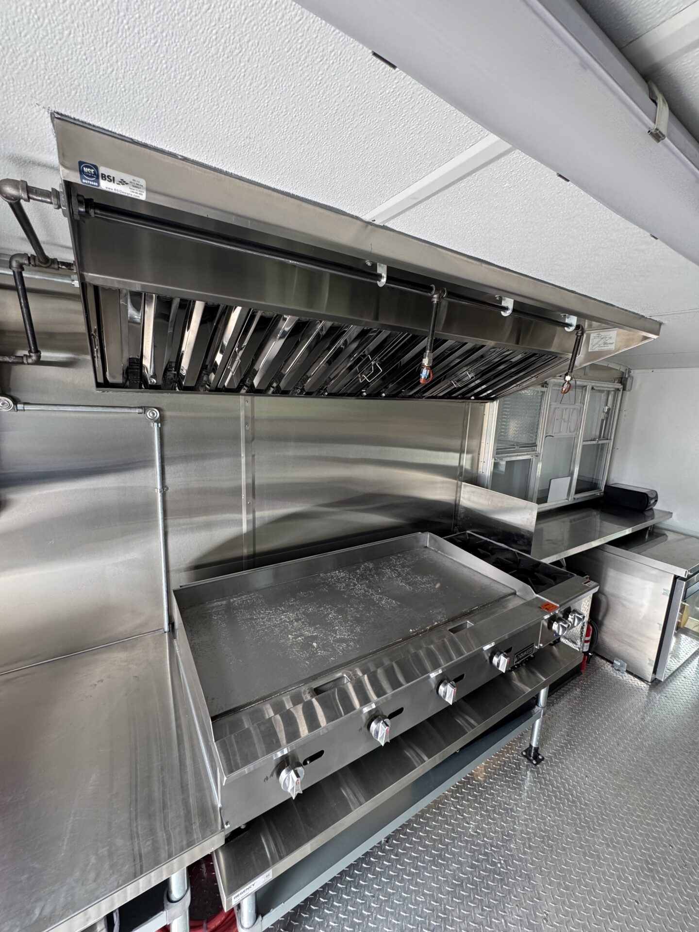 Cooking line of the Hot-Tok Korean food truck showing the 48 inch griddle under the hood vent with the proofer and prep table adjacent