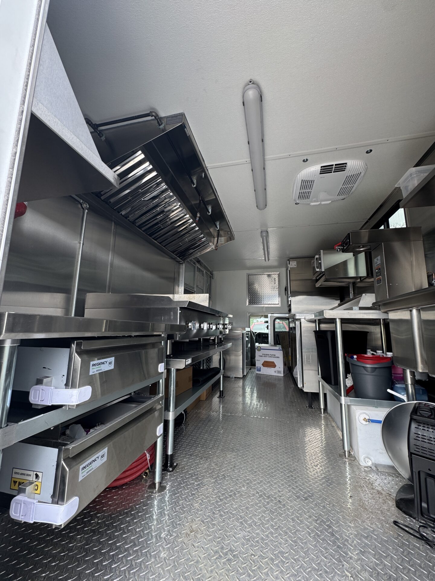 Interior of the Hot-Tok Korean food truck cabin showing the cooking line, three compartment sink, and the kitchen display system mounted at the cooking line