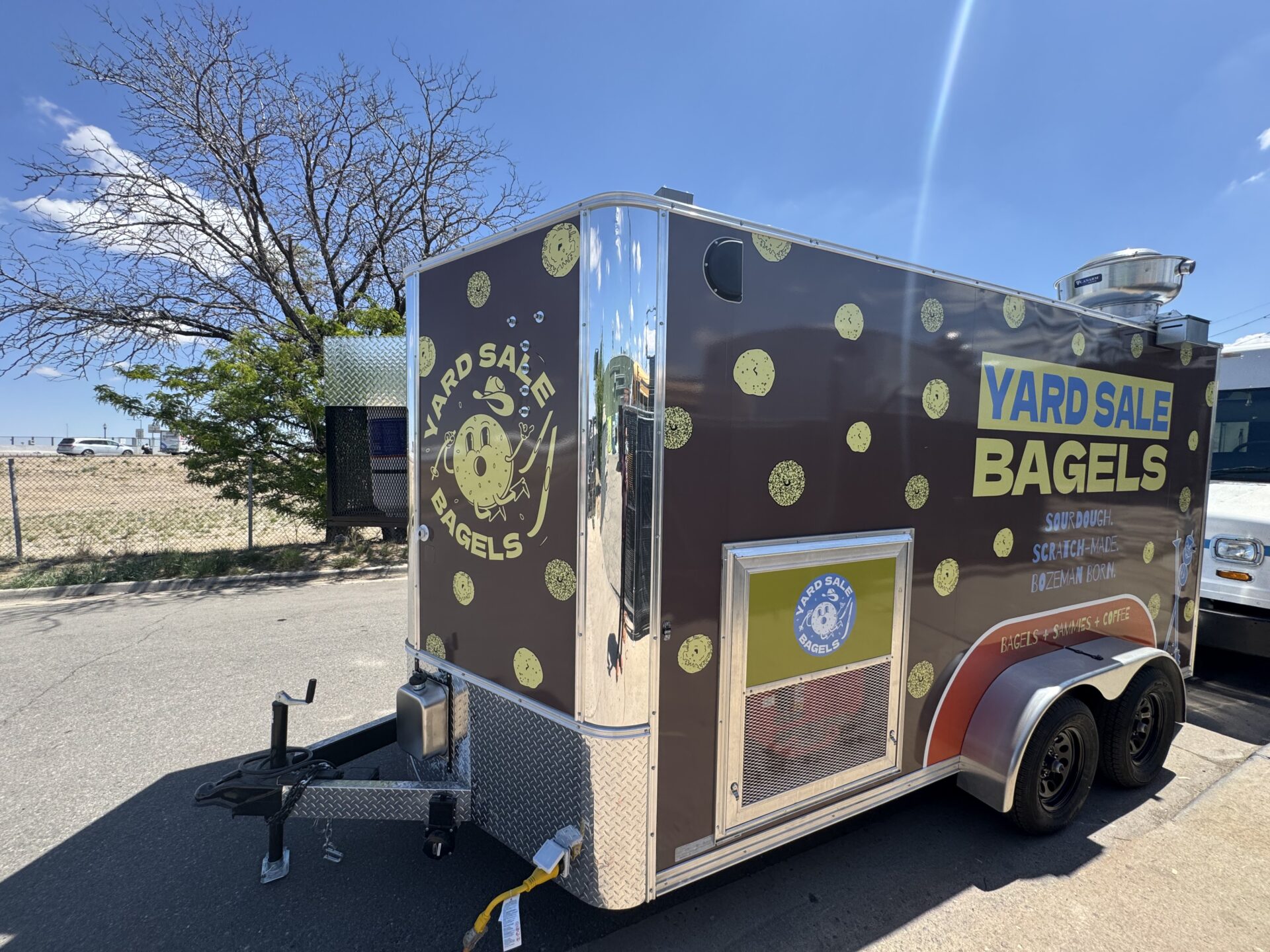 Yard Sale Bagels 14ft bagel trailer from the front three quarter angle showing the Yard Sale Bagels logo and dual axle frame