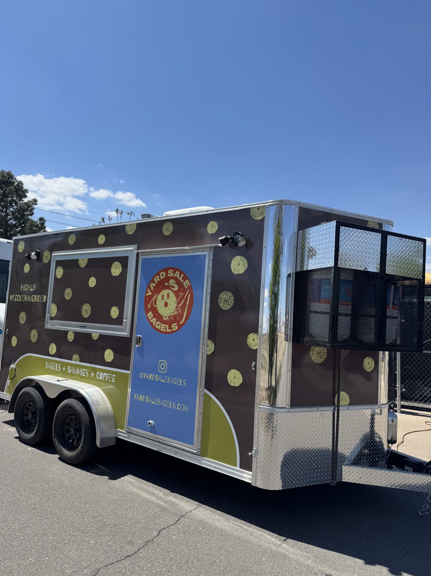 Side view of the Yard Sale Bagels trailer with bagel pattern wrap and Yard Sale Bagels logo on the service window door