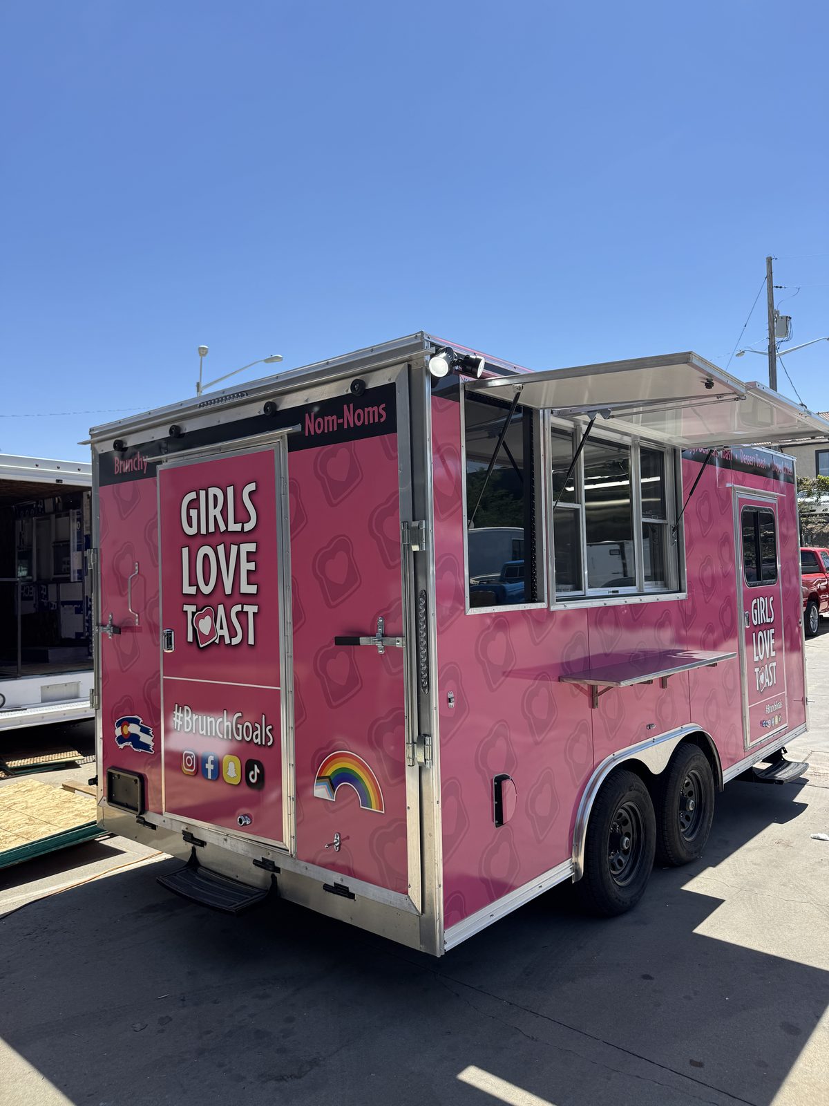 Rear three quarter view of the 16ft food trailer showing the service window, the outside shelf and the man door