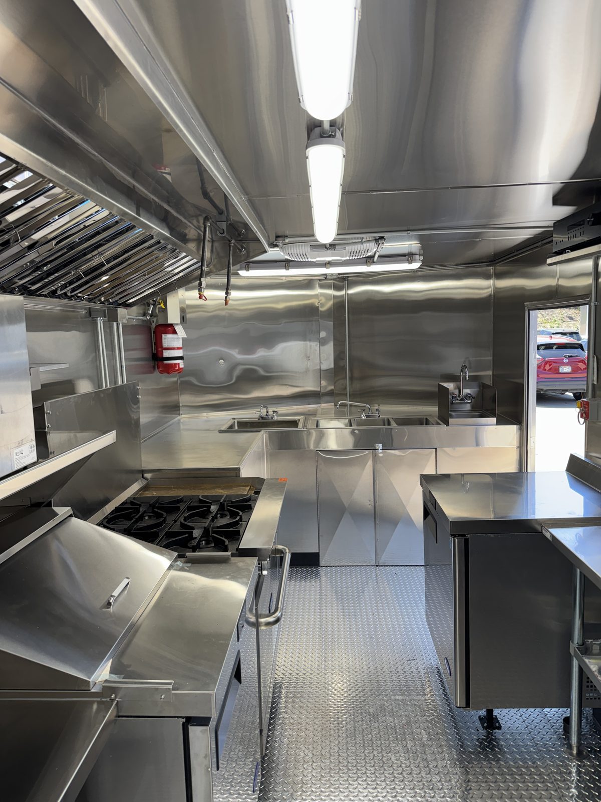 Stainless interior of the 16ft trailer, hood and shadow free LED lighting overhead, sinks along the wall, diamond plate floor