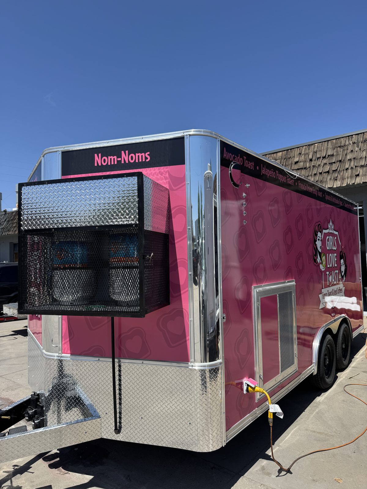 Ventilated mesh cage on the front of the food trailer holding the propane cylinders, with the gas lines run under the floor