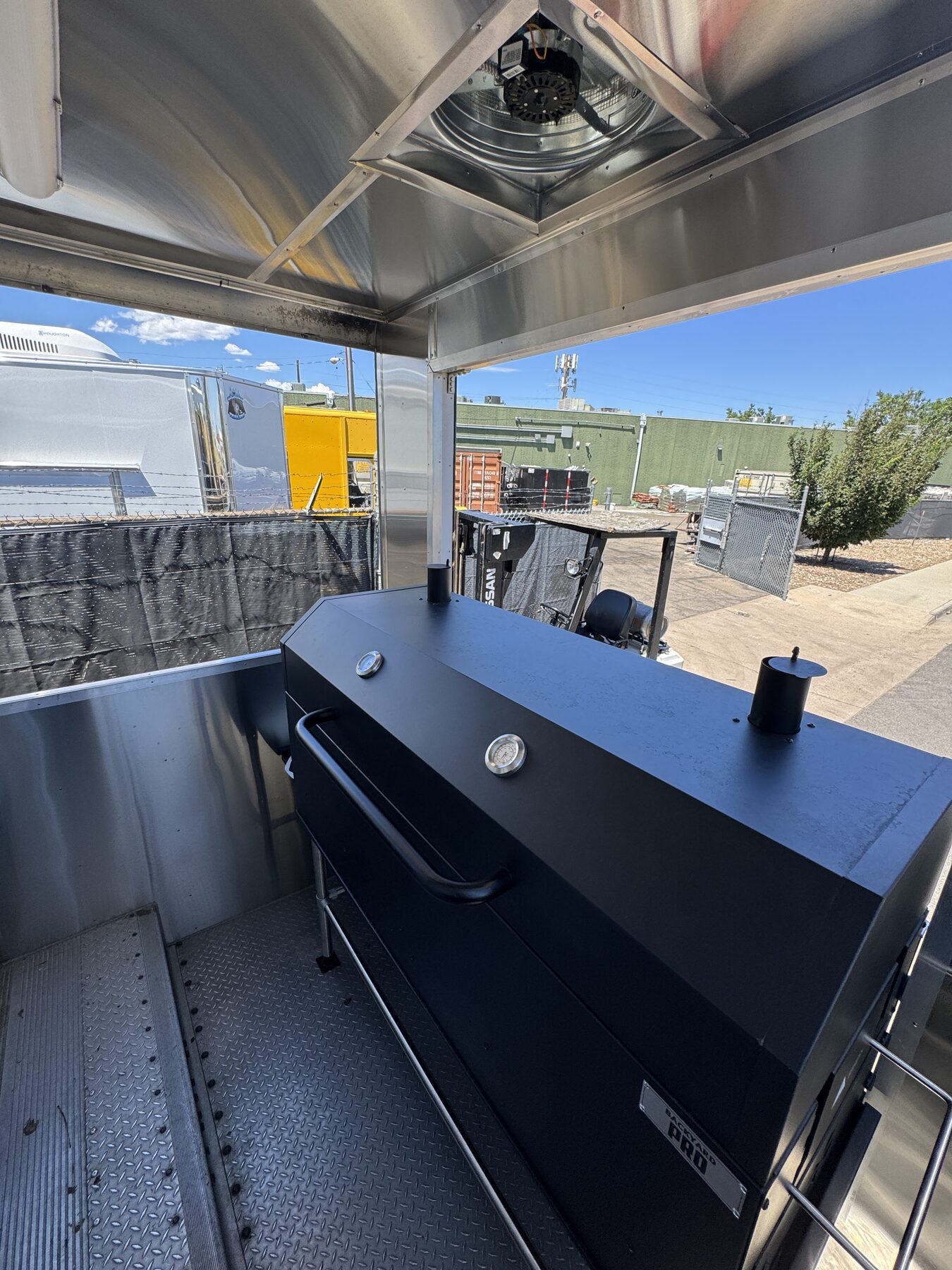 Backyard Pro sixty inch charcoal smoker standing on the open rear porch of the food truck