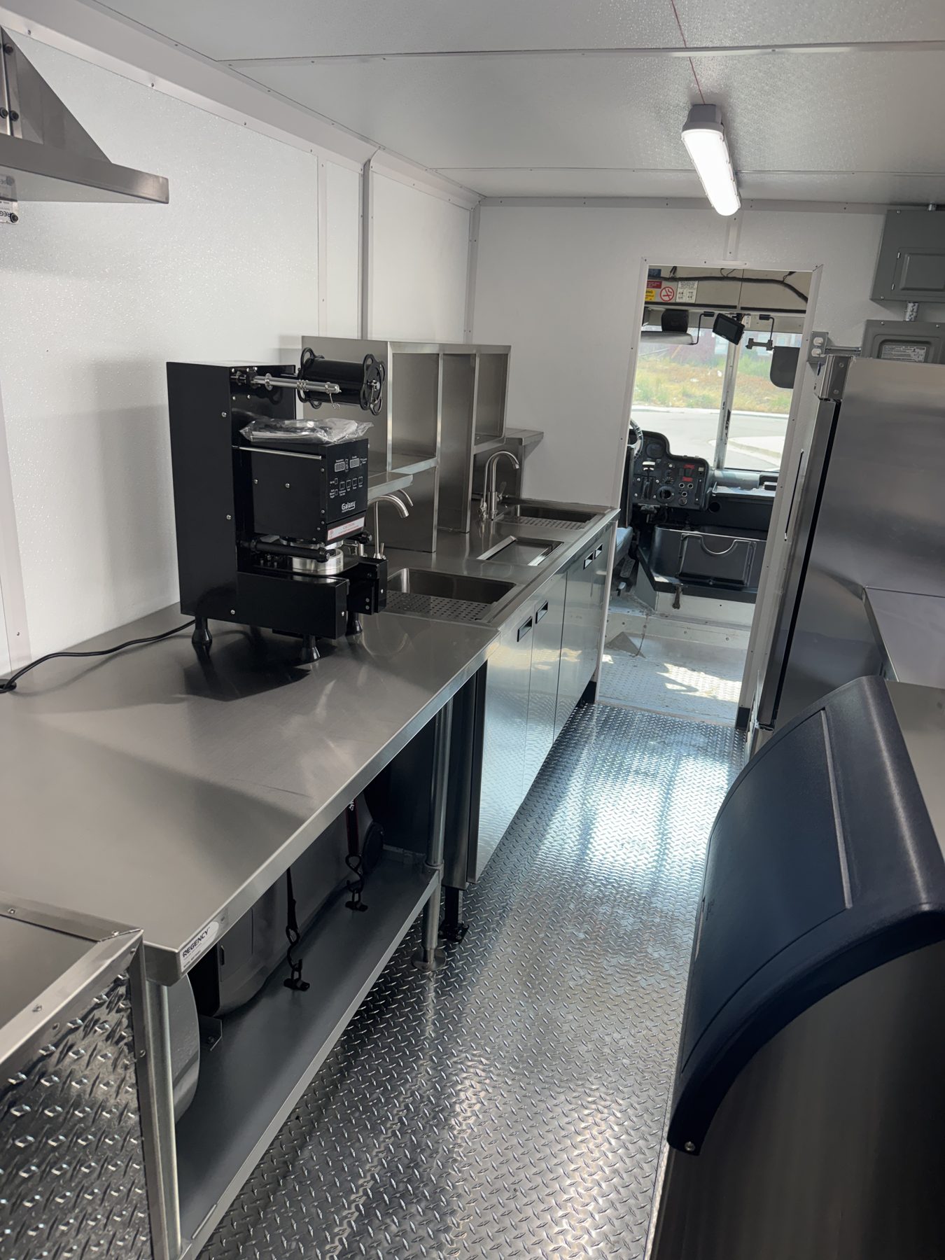 Aisle of the boba tea truck looking forward toward the cab past the cup sealer and ice machine