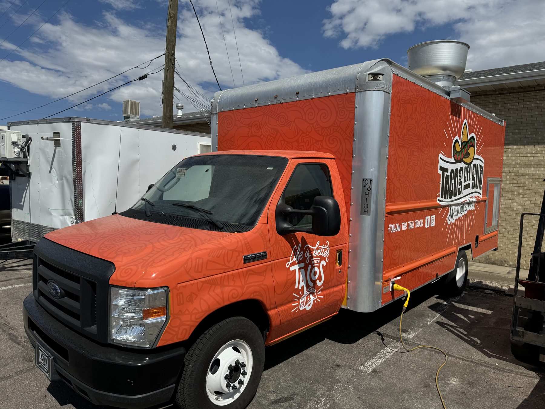 Front three quarter view of the box truck food truck showing the rooftop exhaust fan and wrap