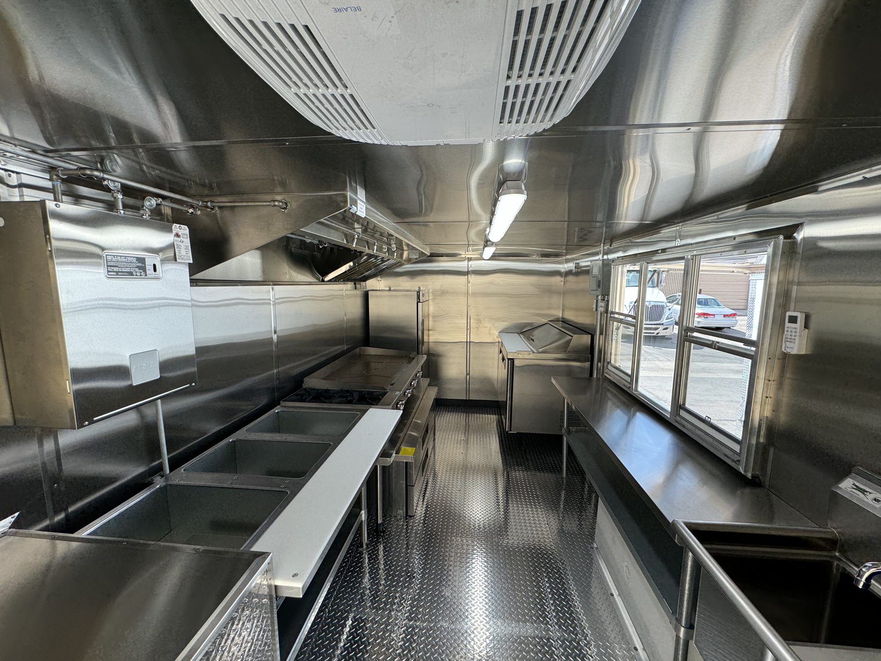 Interior of the taco truck showing the 8ft hood over the cook line and the service window opposite