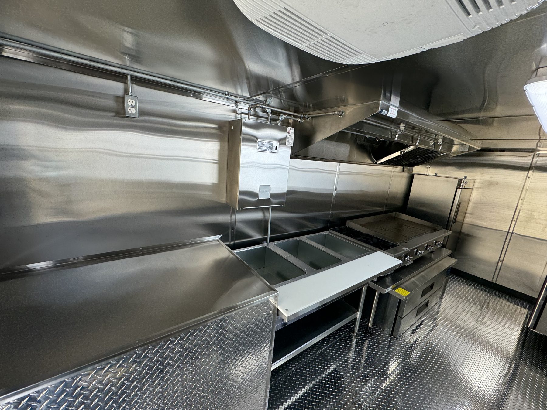 Steam table with cutting board leading to the griddle line inside the taco truck