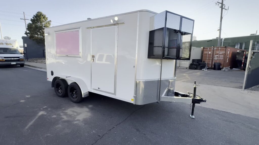 12ft white enclosed food trailer with double axles and a caged propane rack on the tongue, built for El Paso County, Colorado