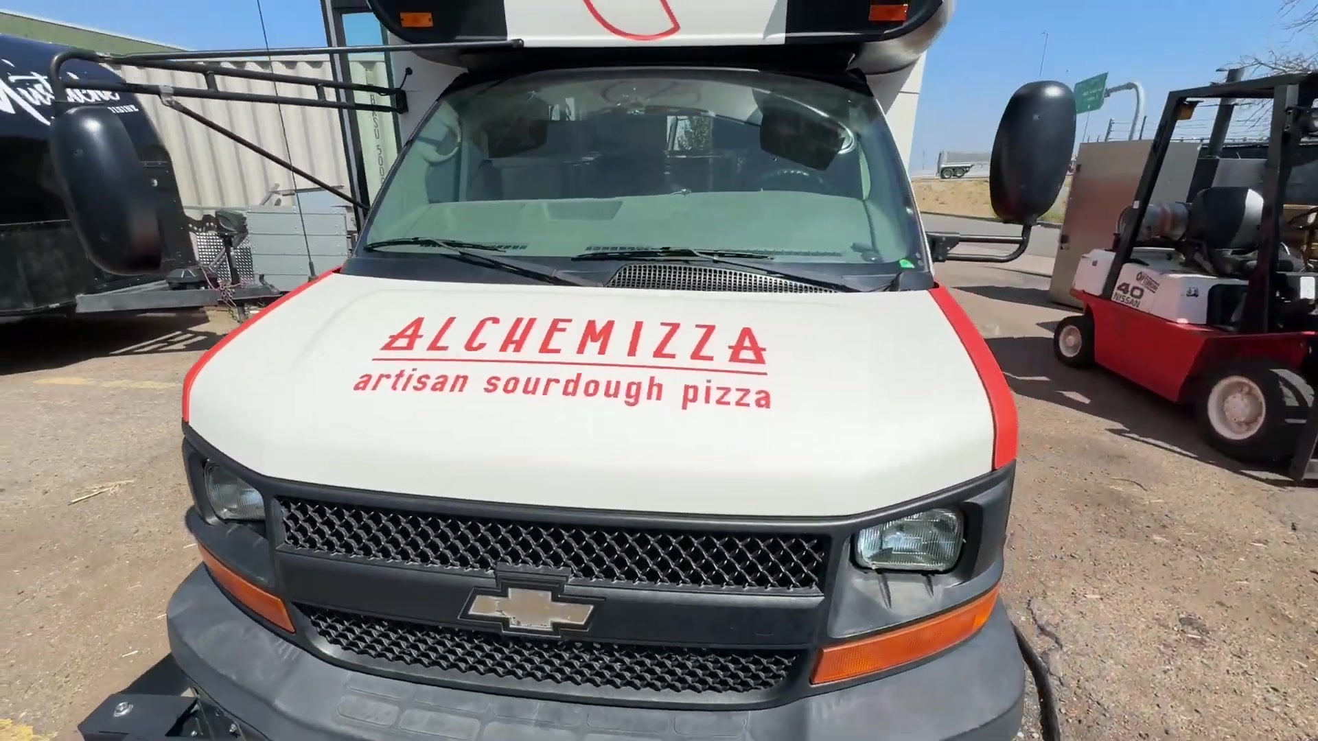 Front of the Alchemizza food bus with artisan sourdough pizza lettering on the hood