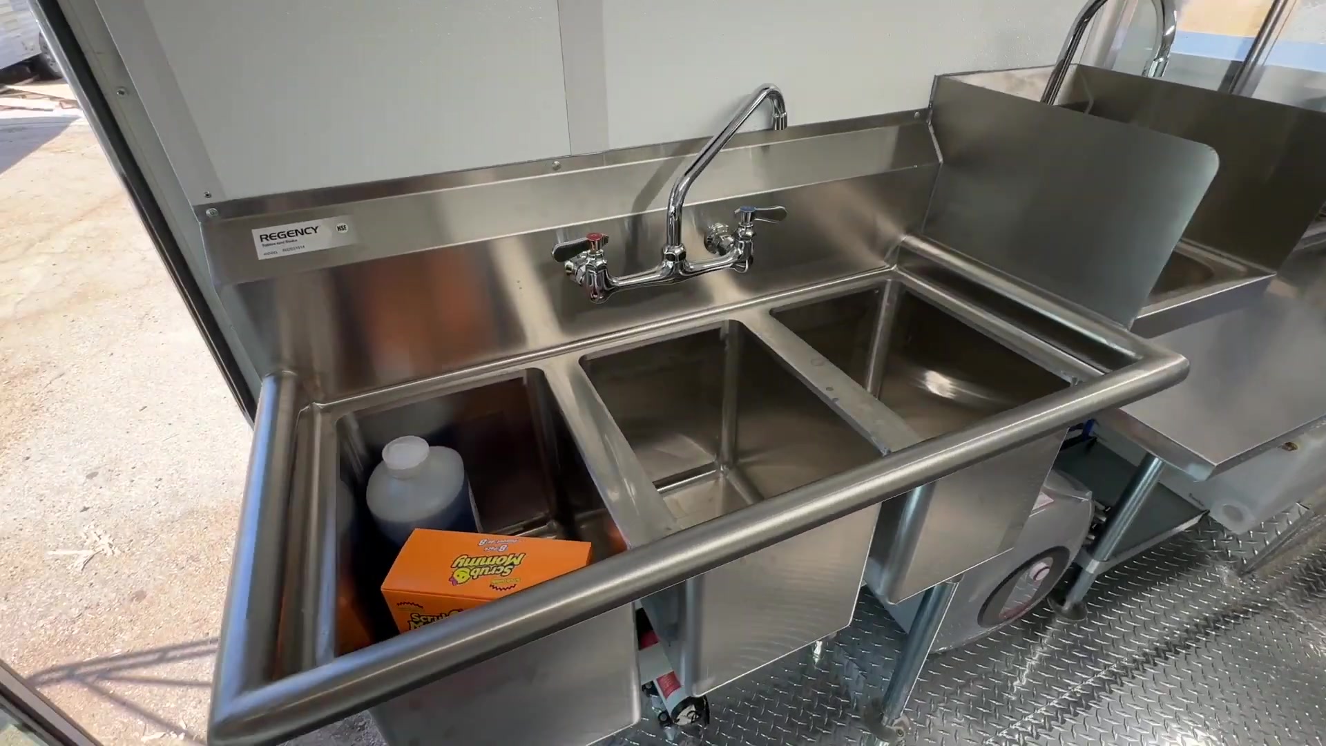 Three compartment sink with drainboard and faucet inside the food bus