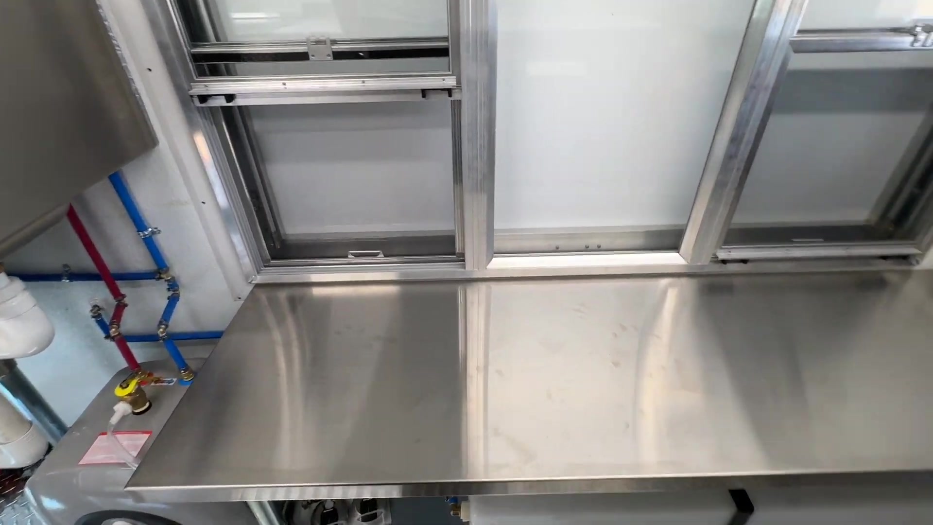 Water heater, pump and hot and cold plumbing lines under the counter of the food bus