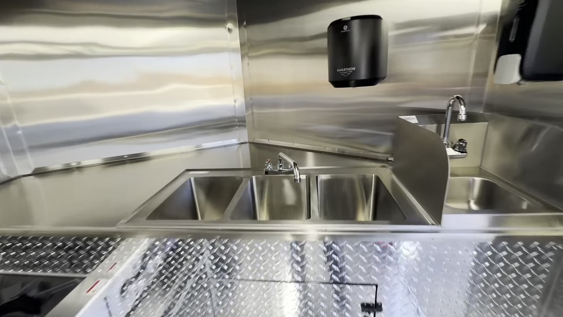 Hand wash sink with splash guard and three compartment sink with towel dispenser in the food trailer