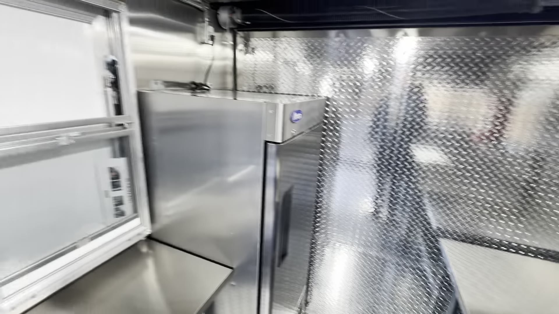 Atosa reach in refrigerator beside the service window inside the 12ft food trailer