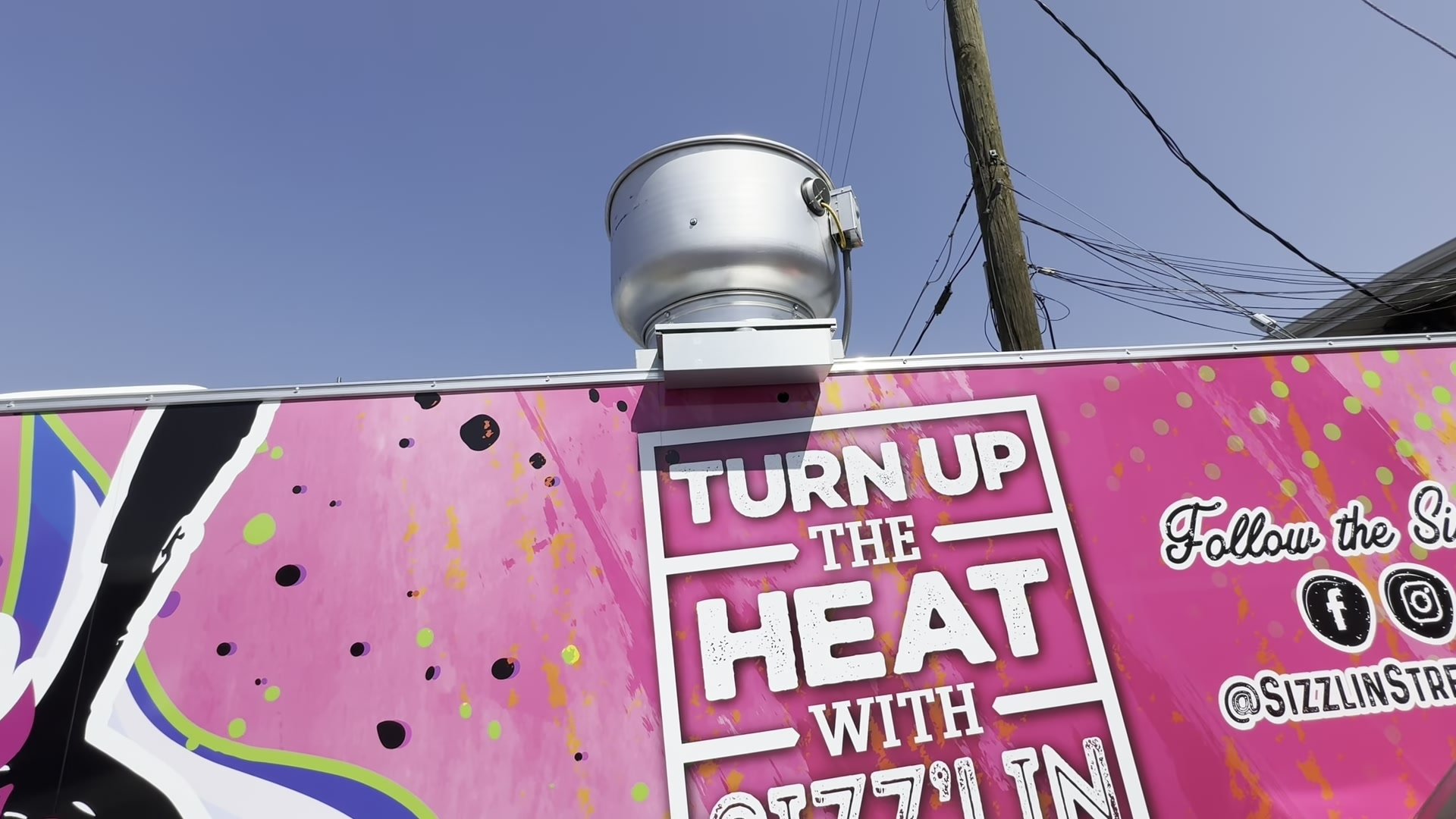 Upblast exhaust fan on the roof of the food trailer above the Turn Up The Heat wrap