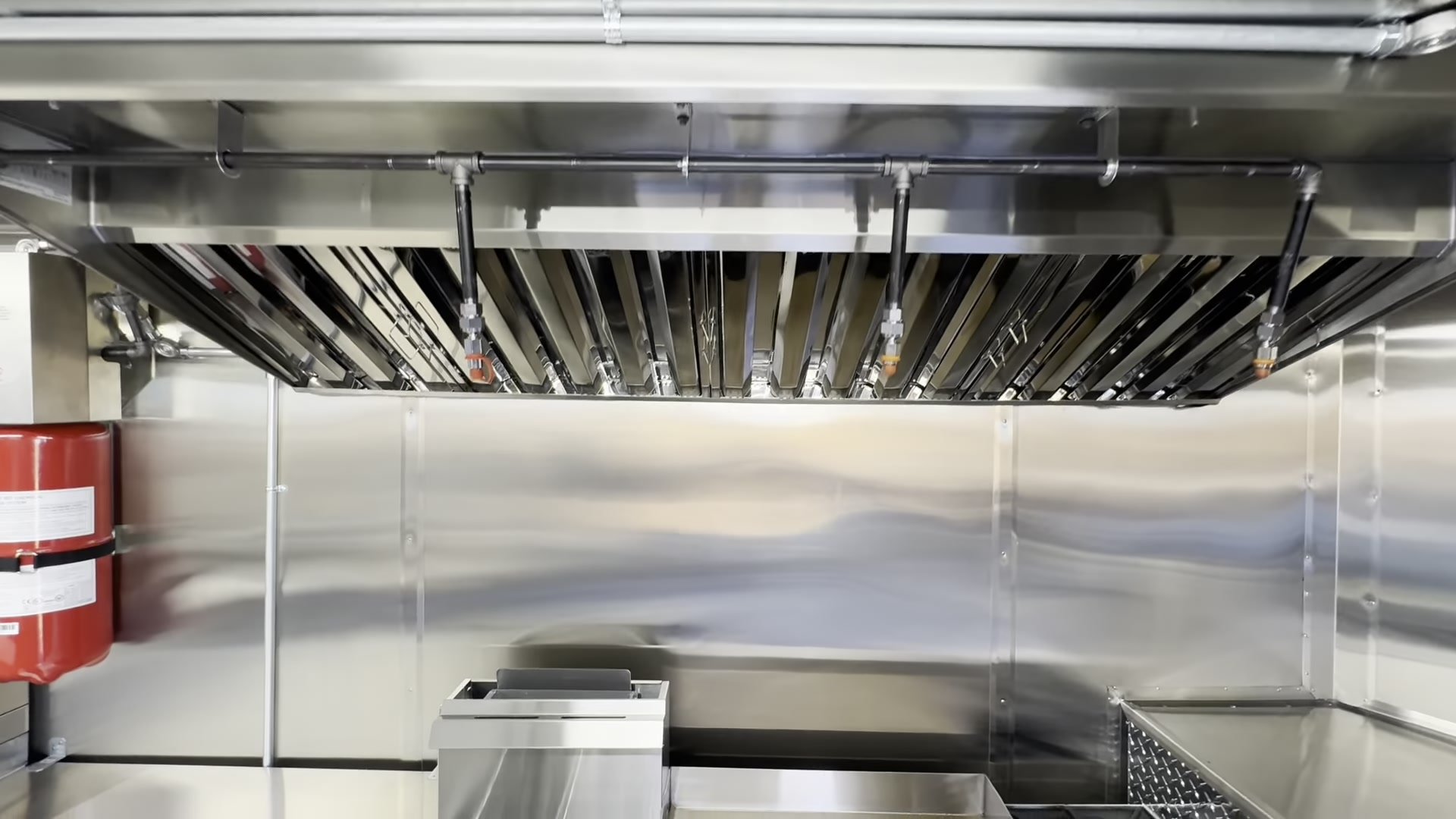 Type 1 hood with fire suppression nozzles over the cook line, with a Class K extinguisher on the wall