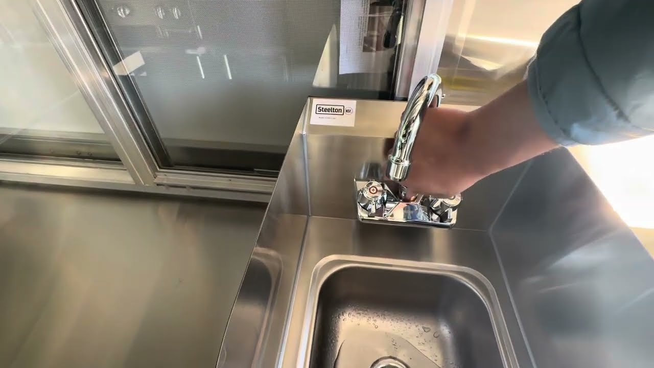 Opening the hand sink faucet to drain the lines while winterizing a food truck