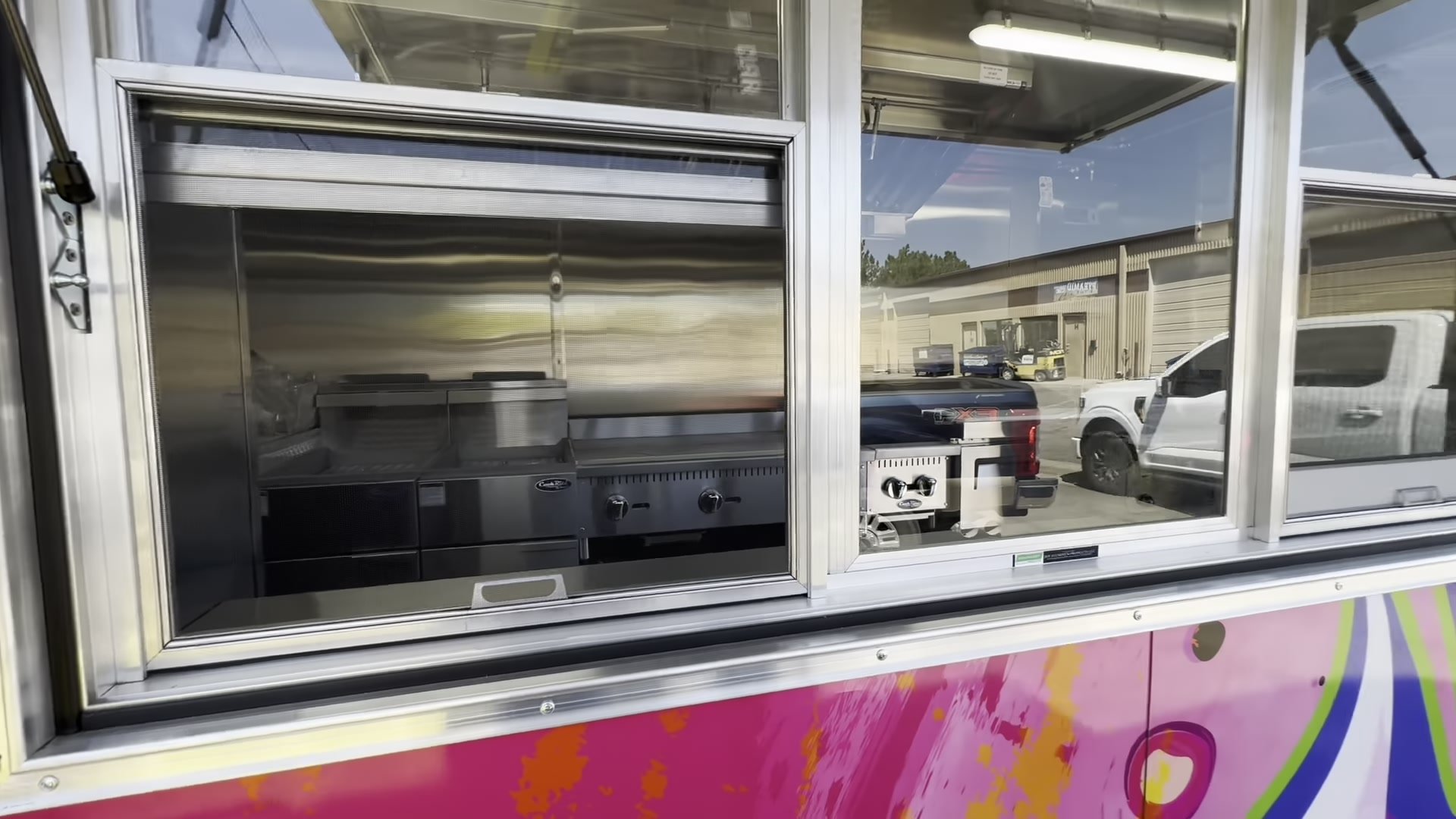Service window of the Sizzlin Street Bites trailer from outside, showing the line inside