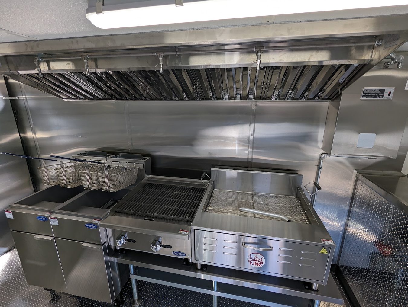 Close view of the flat bottom fryer and radiant charbroiler in the tempura trailer